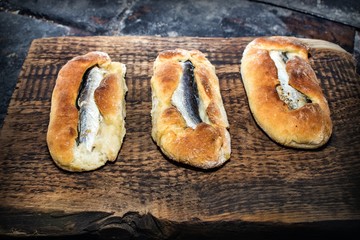 Homemade fish pies on a wooden textured surface against a background of stove brickwork