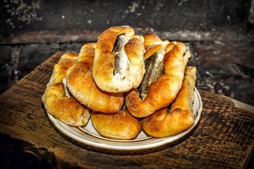 Homemade fish pies on a wooden textured surface against a background of stove brickwork