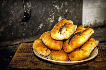 Homemade fish pies on a wooden textured surface against a background of stove brickwork