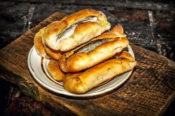 Homemade fish pies on a wooden textured surface against a background of stove brickwork