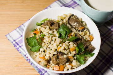 Vegetarian crumbly pearl barley porridge with mushrooms vegetables and herbs in a white plate