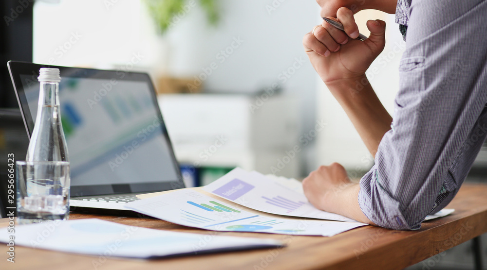 Poster side view of experienced businessman looking at financial data with graphics and charts while work o