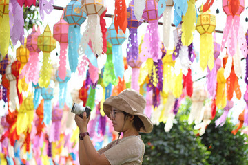 Women photographer hold camera and taking a photo northern Thai Style Lanterns (Yi Peng) Festival, Lamphun, Thailand.