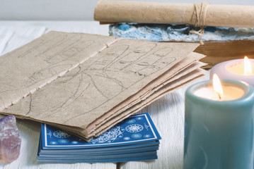 Palmistry book with hand life lines, magic book and tarot cards on white wooden table.