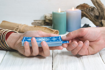 Tarot cards in fortune teller hand on white wooden table background. Future reading.