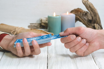 Tarot cards in fortune teller hand on white wooden table background. Future reading.