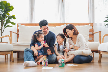Happy Asian family using tablet, laptop for playing game watching movies, relaxing at home for lifestyle concept - Powered by Adobe