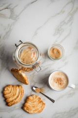 Italienische Blätterteig Fächer Kekse mit Einmachglas und Becher Kaffee auf Marmor Hintergrund