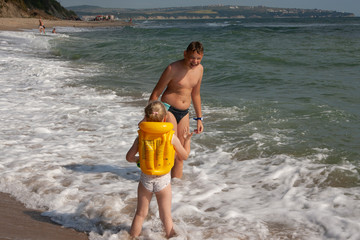 Two children a boy and a girl, a brother and a sister are playing on the seashore in the water.