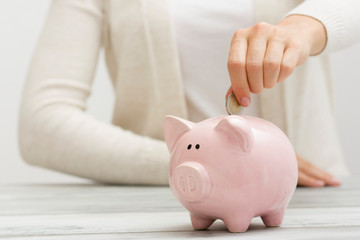 Obraz na płótnie Canvas woman hand putting money coin into piggy for saving money wealth and financial concept.