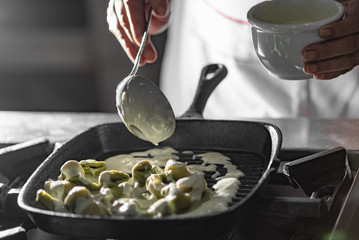 Homemade capeletti pasta with bechamel sauce in an black iron pan. Italian cuisine