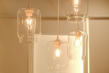 concept loft style, underground style. Four glass electric lamps burn in a bright room on a light warm background.