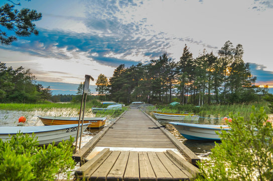 Peaceful cloud landscape above the forest side in Sweden with wooden pathway through the lake water and water reflection of stadinding cannoe