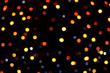 Fototapeta na wymiar Many soft orange, yellow, red and blue blurry bokeh light on dark tone background in Christmas and New Year festival day, can use for background