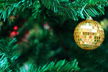 Close up decoration hanging on Christmas tree branches by yellow bauble mirror ball, have blurry...