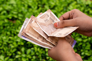 Hands of Young Indian counting new Indian Currency notes in outdoor location