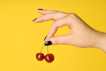 girl holds sweet cherry in hand