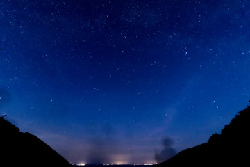 Fototapeta premium Bright starry night with distant town glow