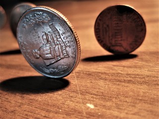 Close-up of several U.S. commemorative and standard coins standing on end, on a wood surface, casting shadow