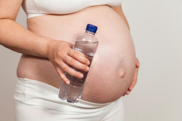 Schwangere hält Flasche Wasser in der Hand