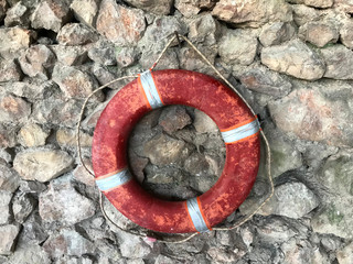 red lifebuoy hanging on stones