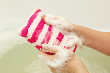 Female hands soaping a striped sponge with soap