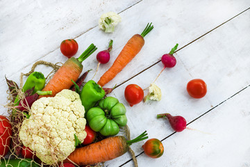 fresh organic vegetables mesh bag on white table top view. cauliflower carrot tomatoes pepper radish 