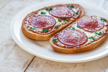 homemade pepperoni pizza sandwiches on white plate close up