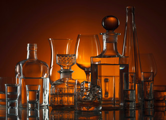 Glassware and alcoholic beverages on a glass table.