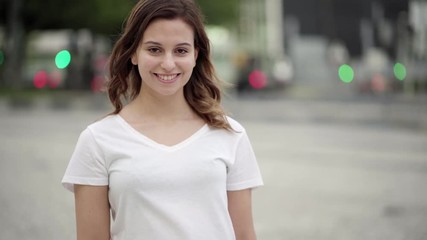Cheerful woman with crossed arms looking at camera. Beautiful young woman posing on street. Female beauty concept