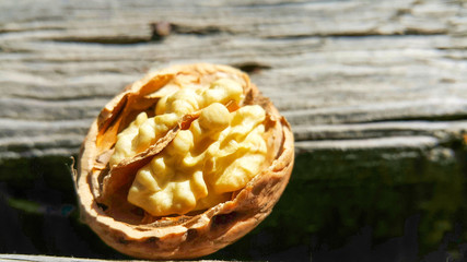 on a wooden background one walnut half of which is open from the peel, close-up and selective focus.