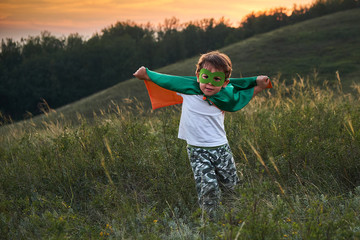 little boy playing a superhero. Kid in an Superhero's costume. happy child runs to meet the photographer. © yavdat
