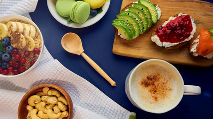 breakfast top view black background. oatmeal with berries, toasts on a wooden tray, nuts, coffee