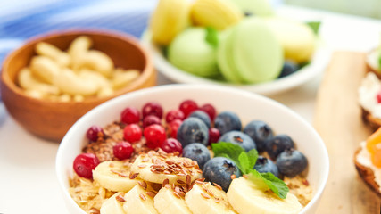 breakfast top view white background. oatmeal with berries, toasts on a wooden tray, nuts, coffee