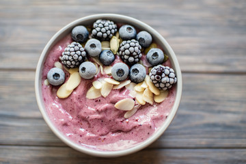 Healthy breakfast berry smoothie bowl topped with banana, granola, Blueberries and chia seeds with...