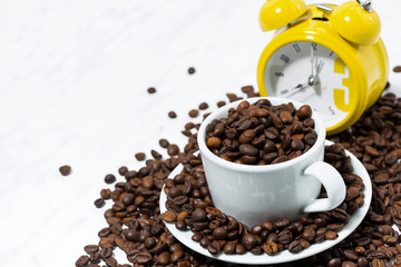 cup with coffee beans and an alarm clock, conceptual photography on white background