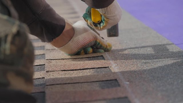 Laying a soft roof. Work at height. Fastening of a sheet of material by means of nails and a hammer.