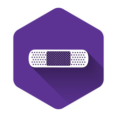 White Bandage plaster icon isolated with long shadow. Medical plaster, adhesive bandage, flexible fabric bandage. Purple hexagon button. Vector Illustration