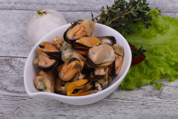 Pickled mussels in the bowl served pepper, garlic and salad
