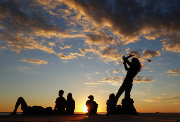 girl juggling poi balls. sunset with colorful clouds background