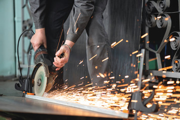 Man is cutting a metal list by angle grinder saw.