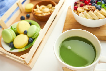 matcha green tea, breakfast top view white background. oatmeal with berries, toasts on a wooden tray, nuts, coffee