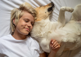 Happy blond woman laying in bed with her shepherd dog