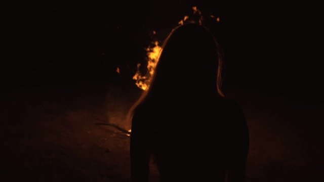 Silhouette of mystic woman in black background of fire fly flame, spark, of contour outline. Outdoor slow motion. Caucasian.