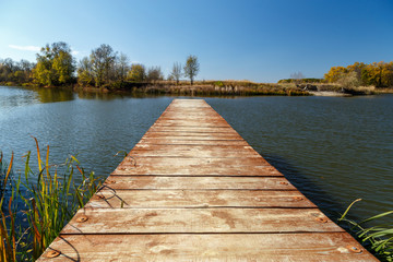 Naklejka premium Old pier on the river on a sunny autumn day.