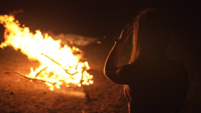 Silhouette of mystic woman in black background of fire fly flame, spark, of contour outline. Outdoor slow motion. Caucasian.