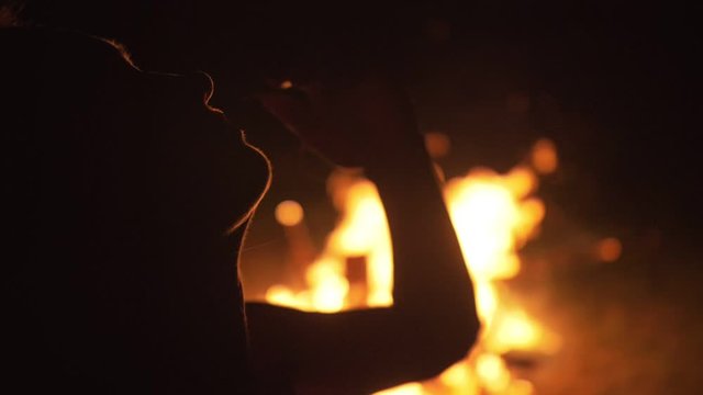 Silhouette of mystic woman in black background of fire fly flame, spark, of contour outline. Outdoor slow motion. Caucasian.