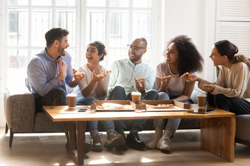 Happy diverse friends eating pizza, talking, having fun at party