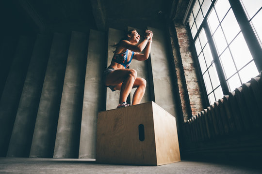 Fitness woman jumping on box while training at the gym,girl doing cross fit exercise. Sports concept, and healthy lifestyle.