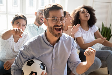 Excited man celebrating goal, watching football with diverse friends